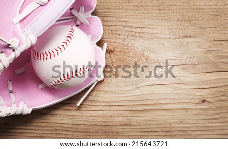 Baseball. Ball in Pink Female Glove over wood background with copy space. 