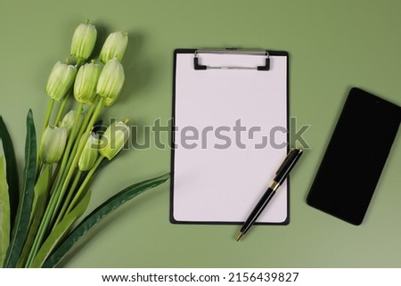 holiday greeting card,  notebook, green tulips on a green background with a phone next to it with copy space, Template for birthday, valentine's day, mother's day, flower pictures.