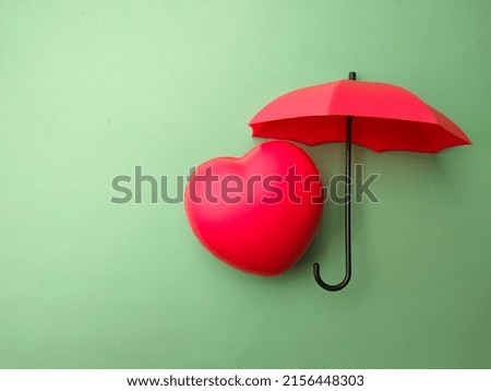 Red heart and umbrella on a green background.