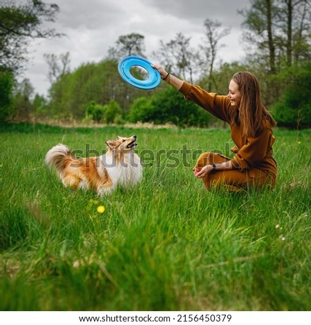 Interaction between dog and owner. Girl playing with her pet outdoors