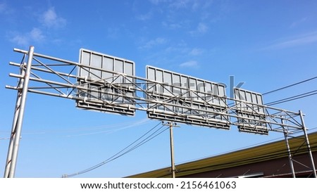 Metal structure signs on the highway. The rear structure of the information board above the road in bottom view on a bright sky background. Selective focus