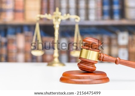 Legal office of lawyers, justice and law concept : Judge gavel or a hammer and a base used by a judge person on a desk in a courtroom with blurred weight scale of justice, bookshelf background behind. Royalty-Free Stock Photo #2156475499