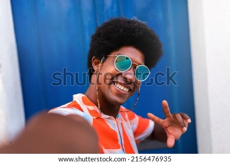 Happy, smiling young African American man taking selfie in coastal Mediterranean village.