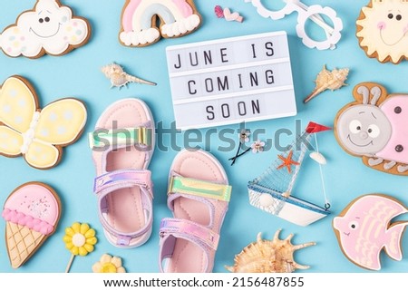 June is coming soon. Motivational quote on light box and cute summer symbols on blue background. Top view, Flat lay. Creative inspirational summer concept.