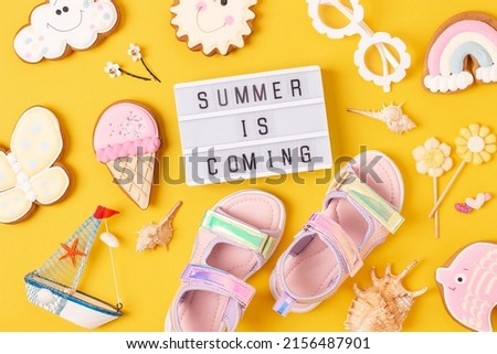 Summer is coming. Motivational quote on light box and cute summer symbols on yellow background. Top view, Flat lay. Creative inspirational summer concept.