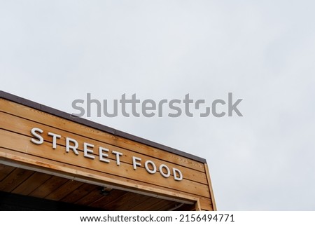 Street food sign hanging against the sky, catering establishment in the city, fast food on the street, concept text fast food, letters on a wooden background. High quality photo