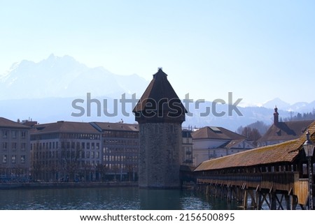 Waterfront with famous water tower and covered wooden Chapel Bridge with Reuss River in the foreground at the old town of Luzern on a spring day. Photo taken March 23rd, 2022, Lucerne, Switzerland.