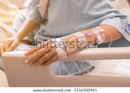 Hands patient woman receiving saline solution during sitting on sick bed at hospital Royalty-Free Stock Photo #2156500965