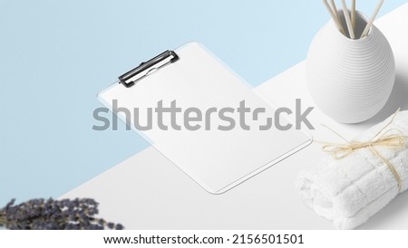 Image with clipboard, lavender flower, white towel, aromatic dispenser and background in colors.