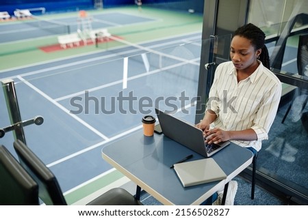 High angle portrait of young black businesswoman using laptop while working in sports training center