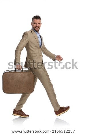 happy bearded man in his 40s with luggage quitting job and going to vacation, walking and smiling in front of white background