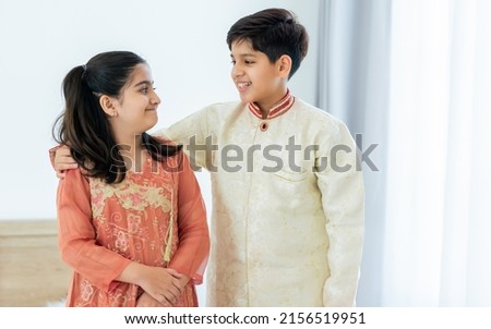 Portrait two people Indian siblings, brother, sister hugging with warmth, love, wearing traditional clothes, smiling with happiness in cozy indoor home. Family, Education, Lifestyle Concept Royalty-Free Stock Photo #2156519951