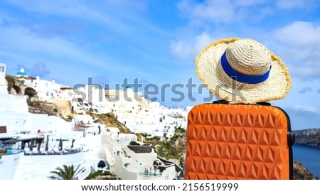 The Banner of travel concept with Orange luggage with hat and landscape view of Oia town in Santorini island in Greece , Greek landscape as blue sky background