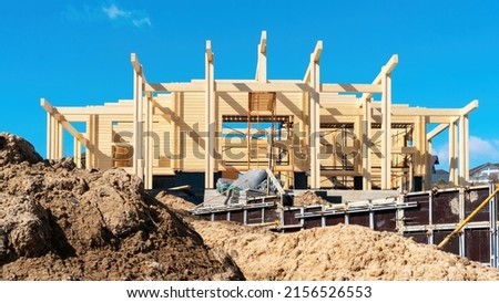 Construction of a wooden house from glued profiled timber in the spring season. The use of formwork for concreting the terrace, the foundation of the fence. Building sand on a construction site.