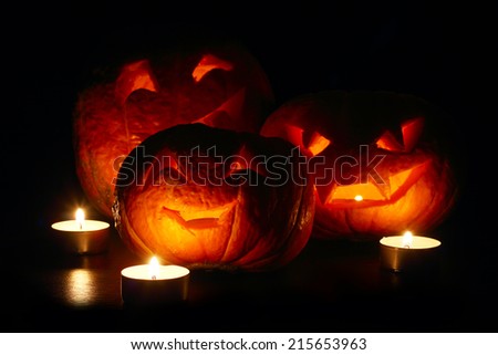 Illuminated cute halloween pumpkins and candles isolated on black background