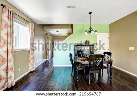 Green and beige dining room with dark brown hardwood floor and black dining table set