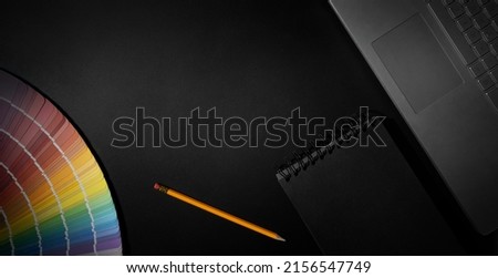 designer workspace with color swatch, laptop and notepad on black background. banner with copy space