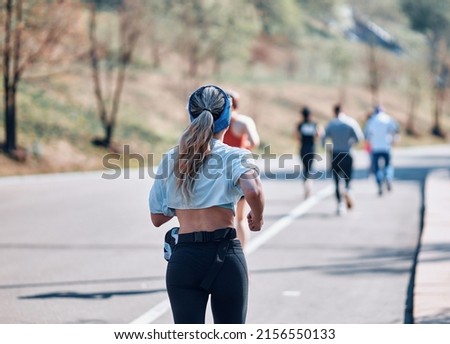 A group of athletes participates in the race on a sunny summer day. View from the back, in the foreground a European girl with long hair.