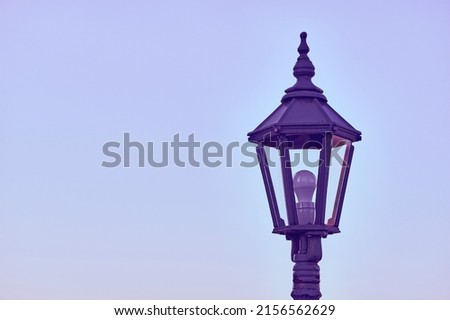 Lonely purple lantern with LED bulb and evening blue calm sky