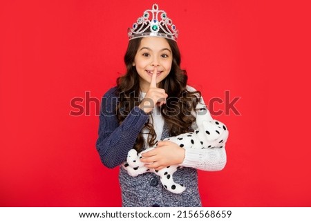 happy child in queen crown. princess in tiara. kid hold toy wth hush gesture.