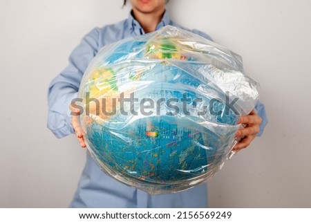 a woman holds a globe of planet earth in a plastic bag. without a face. close-up