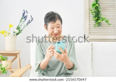 Asian senior woman using the smartphone at home