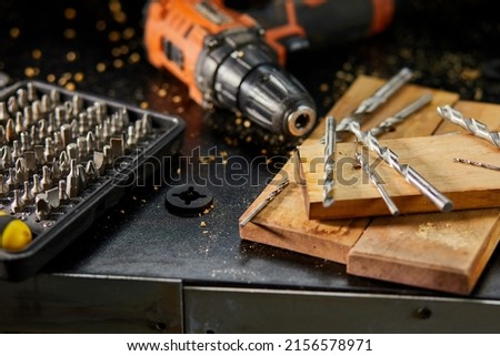 Close up of a metal drill bit set at workshop, carpenter chooses a drill for drilling a wooden block. Royalty-Free Stock Photo #2156578971