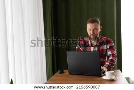Businessman using laptop on wooden table in light cafe with coffee cup, freelancer working remotely on laptop, online work, wireless internet for freelancing, job concept, copy space, place for text