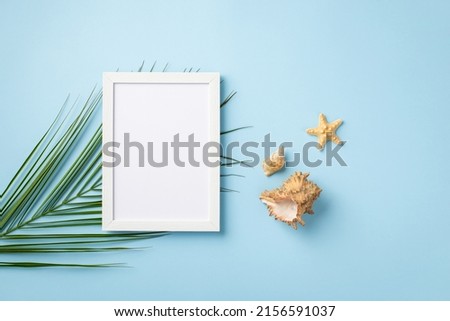 Summer vacation concept. Top view photo of white photo frame starfish shells and palm leaves on isolated pastel blue background with copyspace
