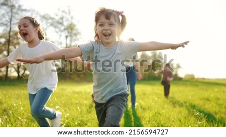 group of children running in the park. happy family baby kid dream concept. kindergarten. children hands to the sides play pilots plane run on the grass in sun the summer in the park Royalty-Free Stock Photo #2156594727