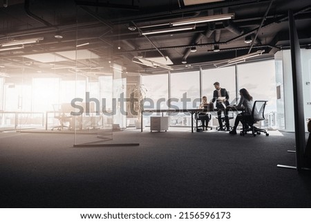 Team of businessmen communicating together in office with panoramic windows. Blurred background