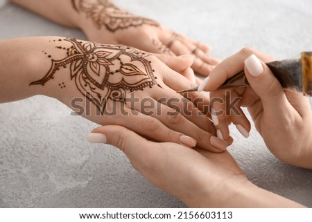 Mehndi master drawing henna tattoo on female hand in salon Royalty-Free Stock Photo #2156603113