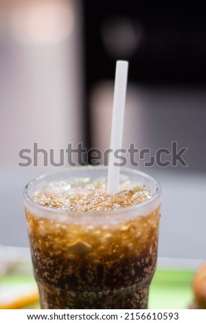 A close up picture of coke with ice and straw in a glass
