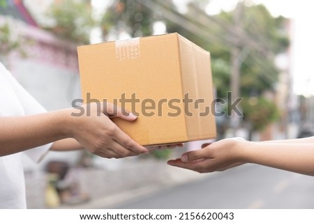 Postal service sending paper cardboard box to customer in front of a house outdoor. Shipping service arrival and send to customer address.  Royalty-Free Stock Photo #2156620043