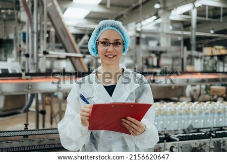 Female worker in protective workwear working in medical supplies research and production factory and checking canisters of distilled water before shipment. Inspection quality control.  Royalty-Free Stock Photo #2156620647