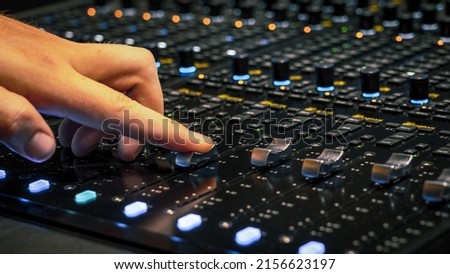 Male hand adjusting the volume on the sound mixing panel