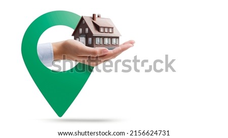 Hand holding a model house and location pin, real estate concept, White background Royalty-Free Stock Photo #2156624731