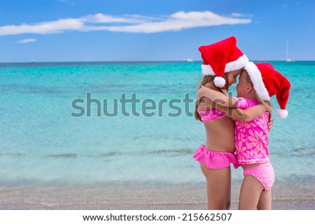 Little cute girls in Santa hats having fun on exotic beach