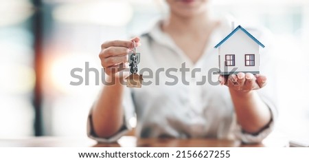Close-up shot of a real estate agent giving new house and house key to her customer.