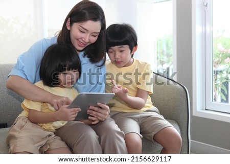 Young joyful casual family of two kids and couple sitting on sofa and Family relaxing on sofa