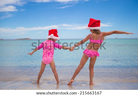 Little cute girls in Santa hats having fun on exotic beach