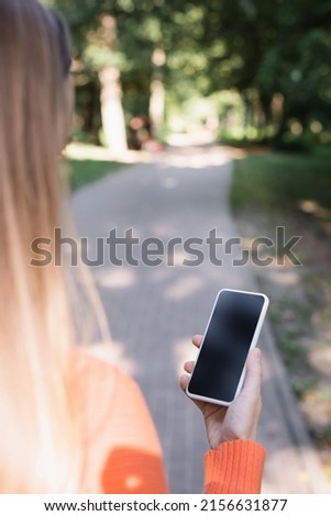 back view of woman holding smartphone with blank screen