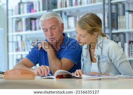man and woman looking at book together in library