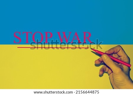 Hand writing in red color the text "Stop War" with the Ukraine Flag as background. 