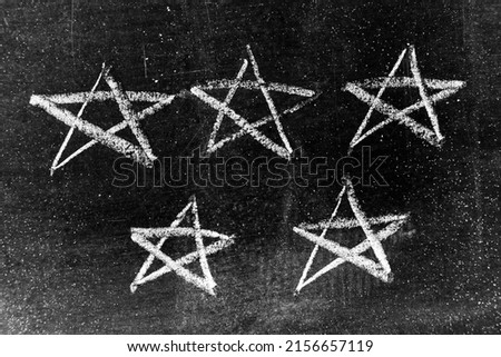 White chalk drawing in star shape on black board background