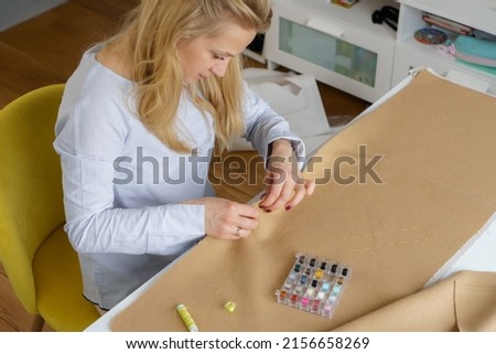 Tailor with needle in hands sews clothing. Woman seamstress at workplace. Closeup needlework Royalty-Free Stock Photo #2156658269