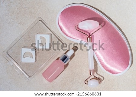 background for cosmetics product presentation with Dissolving Microneedle eye Patches, rose quartz massage roller, sleeping mask and  bottle of cosmetic oil or serum. evening routine before bedtime