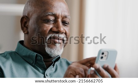Mature elderly old African 60s biracial man using phone American businessman male grandfather free wi-fi chatting mobile app at home browsing net texting message in smartphone internet technology Royalty-Free Stock Photo #2156662705