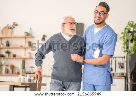 Nurse helping his senior patient to walk with a cane Royalty-Free Stock Photo #2156665949