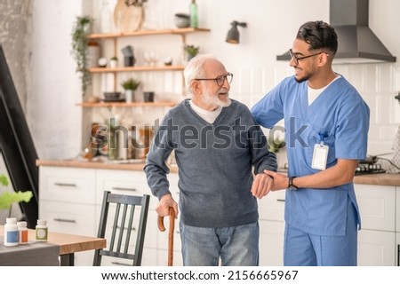 Medical worker helping his patient to move around the apartment Royalty-Free Stock Photo #2156665967